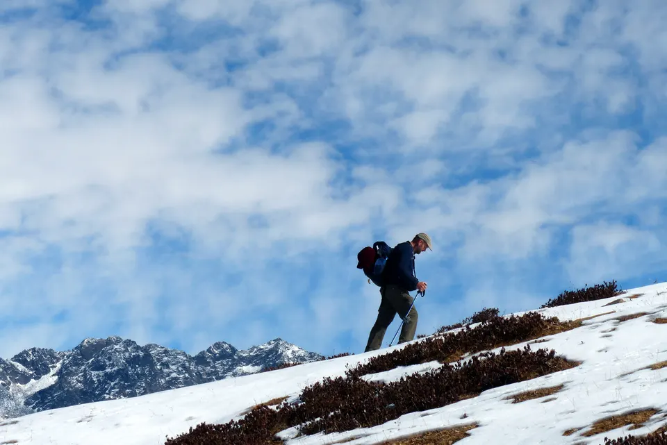 A hiker looking across a snowy mountainside in Uttarakhand